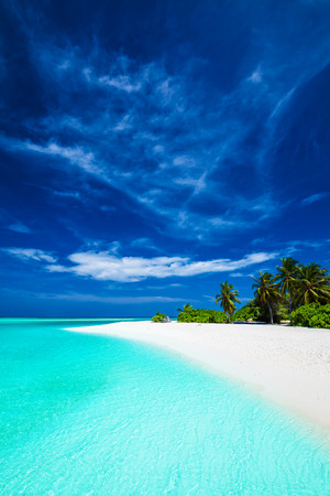 White tropical beach with beautiful sky with few palm trees and blue lagoonの写真素材