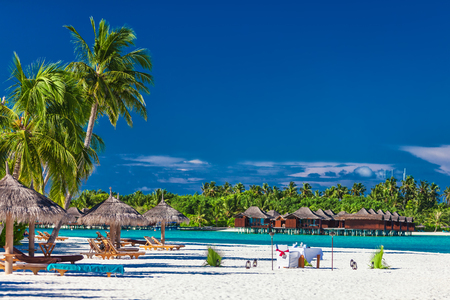 Luxury resort on a tropical island with palm trees and beach umbrellas, Maldivesの写真素材