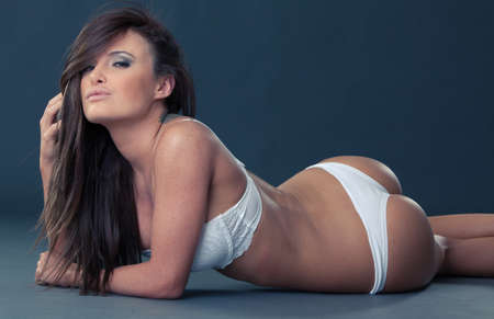 Sexy brunette with long hair in white lingerie with studio lightsの写真素材
