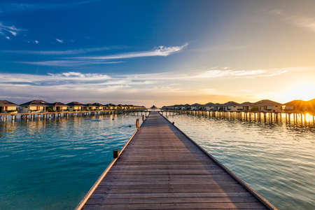 Jetty over swimming atoll and a tropical resort island in Maldivesの写真素材