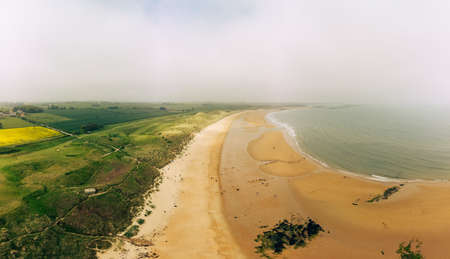 Embleton Bay and Burn with sandy beach with the ruins of Dunstanburgh Castleの写真素材