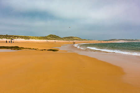 Embleton Bay and Burn with sandy beach with the ruins of Dunstanburgh Castleの写真素材