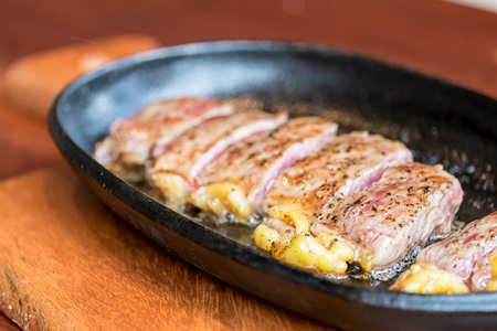 Beef steak in hot pan on wooden tableの写真素材