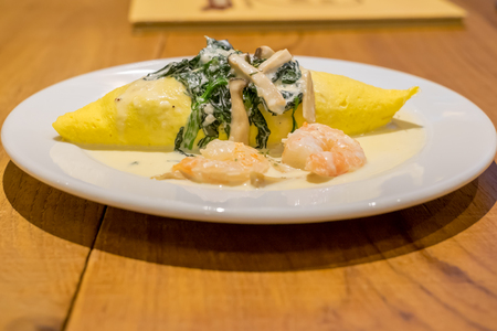 white souce,Fried Rice in an Omelet Wrapping with spinach and mushrooms on white plateの写真素材