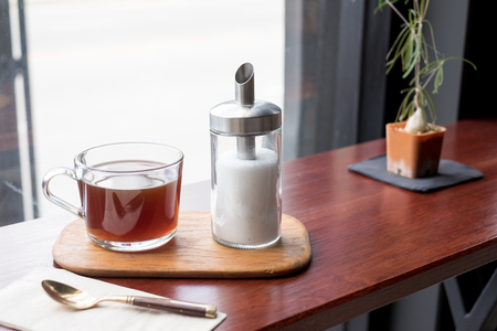Glass of tea with sugar on wooden Coaster in restaurantの写真素材
