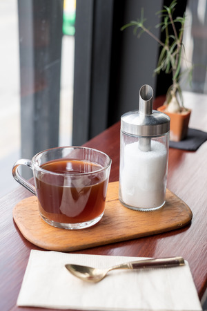 Glass of tea with sugar on wooden Coaster in restaurantの写真素材