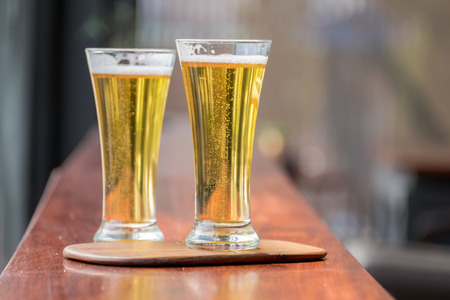 Glass of Beer on wooden table in restaurantの写真素材