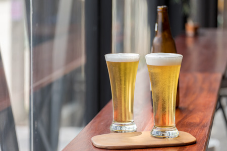 Glass of Beer on wooden table in restaurantの写真素材