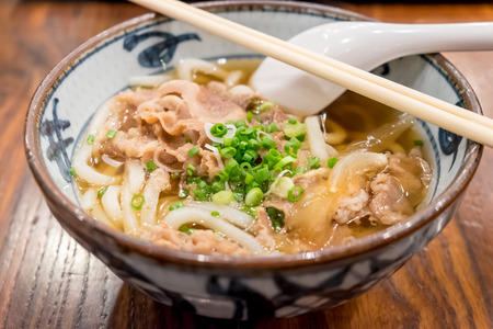 Japanese Udon with beef, onion and soup on wooden tableの写真素材
