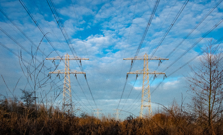 Electrical wires against a blue sky with clouds in the winter in the netherlandsの写真素材