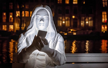 White sculptures of people looking at phone at amsterdam light festivalのeditorial素材