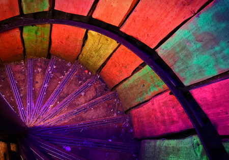 Multi-colored metal spiral staircase in old lighthouse with dirtの写真素材