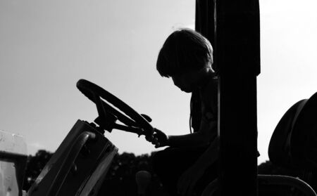backhoe tractor with boy silhouette, isolated on white background, england knockhatchの写真素材