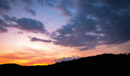 Evening sunset with trees silhouette over English countryside landscape from a hill peak in...