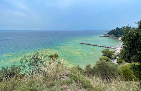 water of lake garda in italy surrounded by mountains in the summerの写真素材