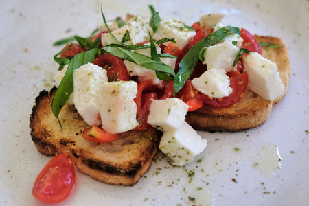 burnt toast with mozzarella and tomato on a plate