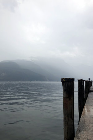 poles in a tranquil lake garda surrounded by mountainsの写真素材