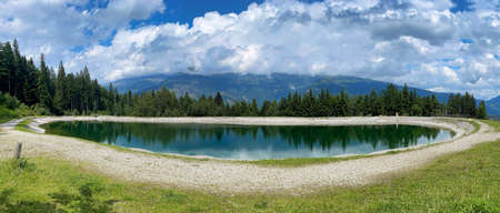 blue mountain lake with grass and trees clouds blue sky austriaの写真素材