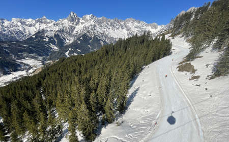 yellow chairlift with snow and trees underneath the blue sunny sky above the ski slopes at wintersport in austriaの写真素材
