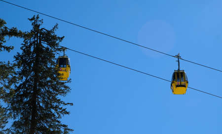 yellow chairlift with snow and trees underneath the blue sunny sky above the ski slopes at wintersport in austriaの写真素材