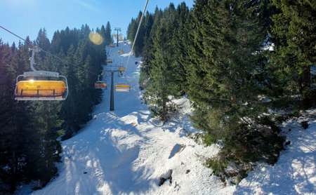 chairlift with snow and trees underneath the blue sunny sky in austria