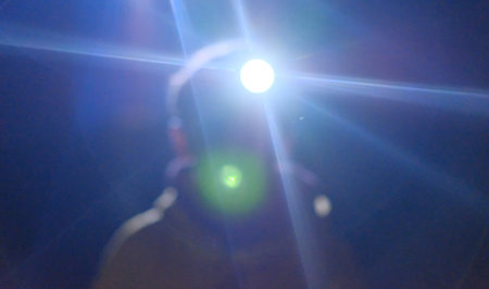 boy with flashlight on head in the dark shines in camera at nightの写真素材