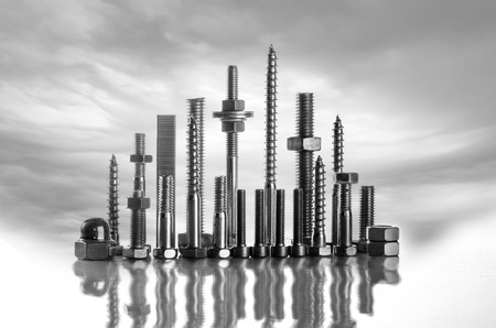 A skyline made of long screws, bolts, nuts on a white background with wild cloudsの写真素材