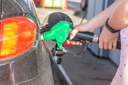 Car gas nozzle refuel fill up with petrol gasoline at a gas station.  Pretty young woman refuel the...