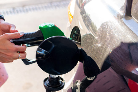 Car gas nozzle refuel fill up with petrol gasoline at a gas station.  Pretty young woman refuel the...