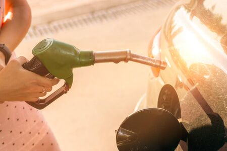 Car gas nozzle refuel fill up with petrol gasoline at a gas station.  Pretty young woman refuel the car. Transportation and ownership concept.の写真素材