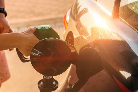 Car gas nozzle refuel fill up with petrol gasoline at a gas station.  Pretty young woman refuel the car. Transportation and ownership concept.の写真素材