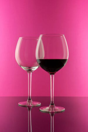 Studio shot of a glass of red wine isolated on pink background closeup. Clean and minimal. Red wine in a big glass. Wine concept.の写真素材
