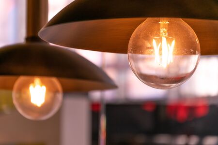 Light, design and interior. Vintage metallic lantern in cafe. Close up two yellow lamp in cafe at nightの写真素材