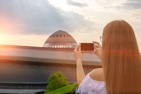 Girl makes a photo on the phone at sunset.の写真素材