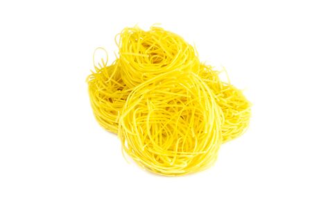 Raw yellow italian pasta pappardelle, fettuccine or tagliatelle close up. Homemade dry ribbon noodles, long rolled macaroni or uncooked spaghetti isolatedの写真素材