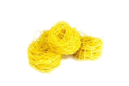 Raw yellow italian vermicelli isolated on white background. Ribbon noodles, long rolled macaroni or uncooked spaghetti isolatedの写真素材
