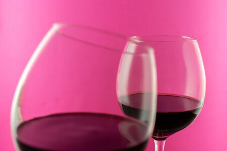 Studio shot of a glass of red wine isolated on pink background closeup. Clean and minimal. Red wine in a big glass. Wine concept.の写真素材