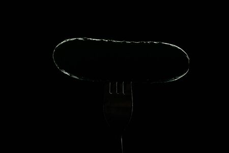 Fresh, green cucumber on fork isolated on black background for salad. Healthy eating concept. With clipping path.の写真素材