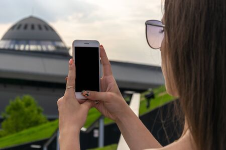 Girl makes a photo on the phone at sunset.の写真素材