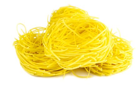 Raw yellow italian pasta pappardelle, fettuccine or tagliatelle close up. Homemade dry ribbon noodles, long rolled macaroni or uncooked spaghetti isolatedの写真素材