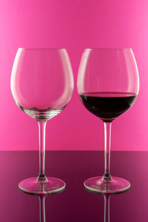 Studio shot of a glass of red wine isolated on pink background closeup. Clean and minimal. Red wine in a big glass. Wine concept.の写真素材