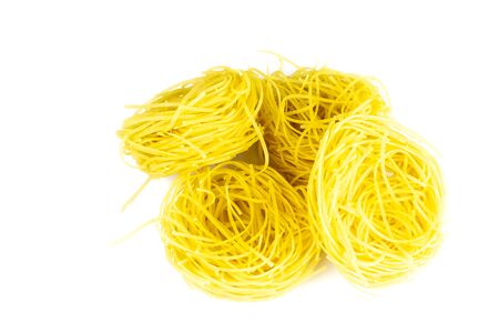 Raw yellow italian pasta pappardelle, fettuccine or tagliatelle close up. Homemade dry ribbon noodles, long rolled macaroni or uncooked spaghetti isolatedの写真素材