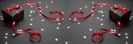 Merry Christmas and Happy Holidays greeting card, frame, banner. Christmas gifts, ornaments on black background top view. Winter holiday xmas theme. Flat lay.の写真素材