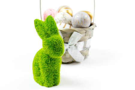 Easter background white. Easter composition: golden shine decorated eggs in basket with green bunny....