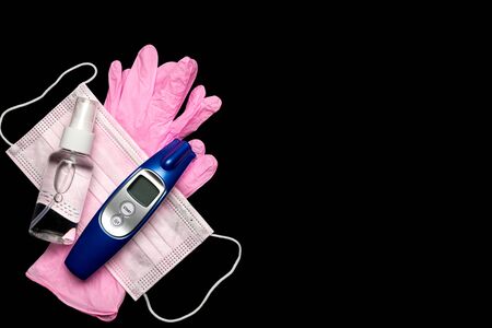 Virus protection. Medical surgical mask, sanitizer gel, Electronic thermometer and lab gloves on black background. Risk Coronavirus disease COVID-19 pandemic concept. Medical respiratory bandage faceの写真素材