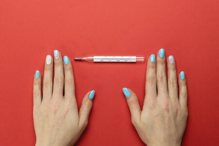 Womans hands use Medical thermometer to check temperature - Virus protection equipment on red background. Coronavirus protection Preventive Measures. Novel 2019-nCoV. Professional safety, hygiene.の写真素材