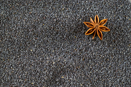 Poppy pattern seeds with anise star. Black poppyseed texture in top view. Pile food dark background....