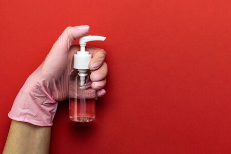 Sanitizer bottle, Medical antibacterial sanitizer gel, lab gloves - Virus protection equipment on red background. Clear sanitizer in pump bottle. COVID middle East respiratory syndrome coronavirusの写真素材