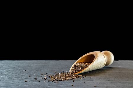 Healthy chia flax seeds food. Pile superfood in wooden spoon on black background. Vitamin antioxidant breakfast or morning snack diet eating conceptの写真素材