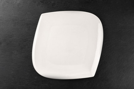 White porcelain plate on table. Dinner background. Empty round round isolated on stone background. Restaurant kitchen minimalistic concept.の写真素材